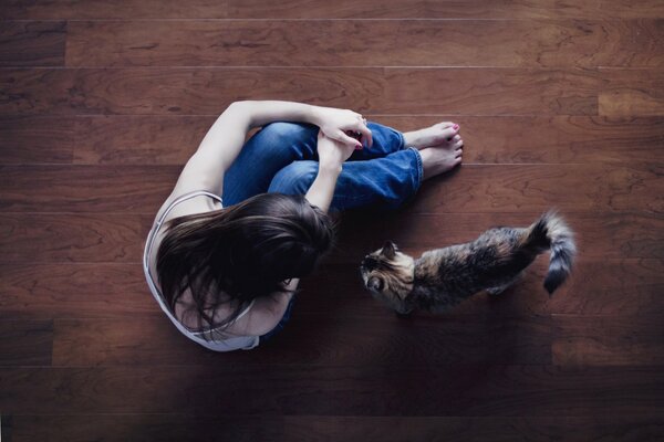 Mädchen sitzt mit Katze auf dem Boden