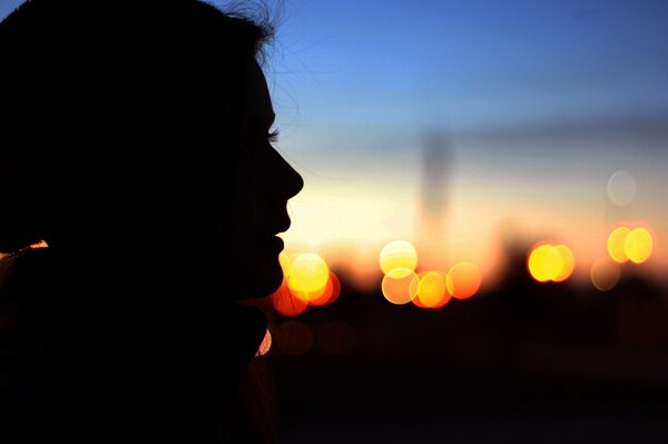Perfil de la chica en el fondo de la puesta de sol de la ciudad