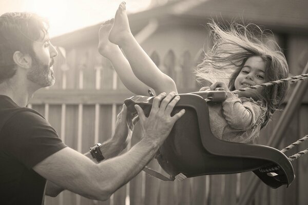 Un uomo cavalca una bambina su un altalena