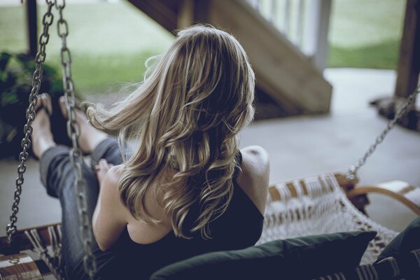 Girlish hair on a swinging swing