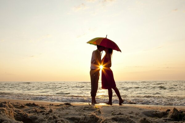 Amanti sullo sfondo del tramonto sul mare con ombrello in mano
