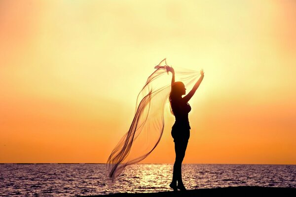 Silhouette d une jeune fille près de la mer au coucher du soleil