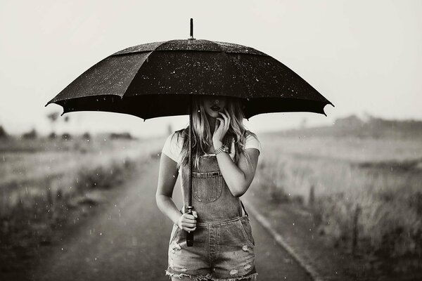 Y está lloviendo y una chica en el camino con un paraguas