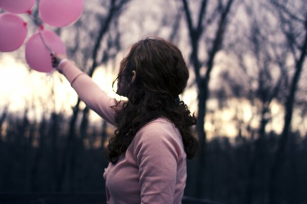 Ragazza in possesso di palloncini di colore rosa dietro di lei sono sfondo sfocato
