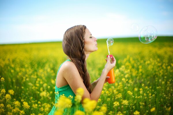 A girl in the field blows soap bubbles