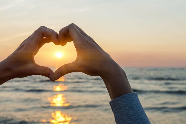 Sole nel cuore dalle mani sopra il mare