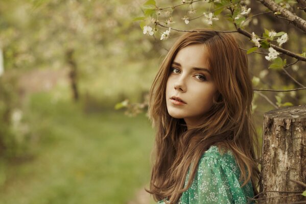 Pensive girl in green by the fence