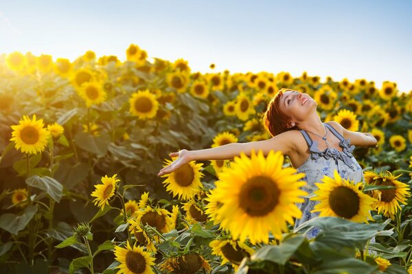 Positives Mädchen auf einem Sonnenblumenfeld