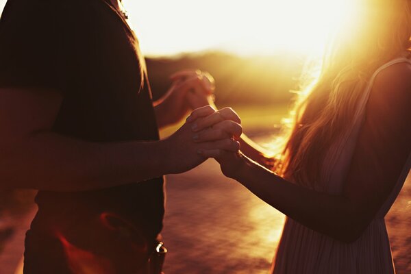 Deux amoureux se tiennent la main sur fond de coucher de soleil