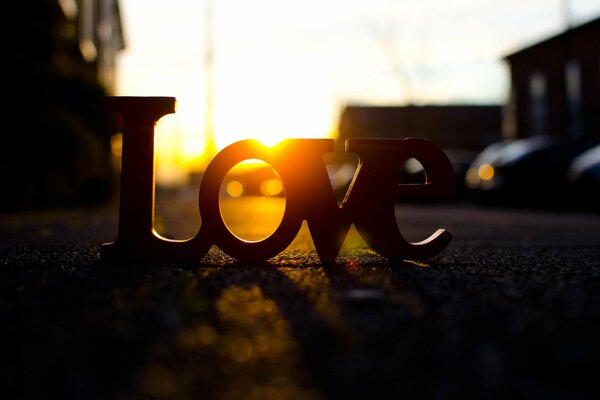 The inscription love on the asphalt in the sunset