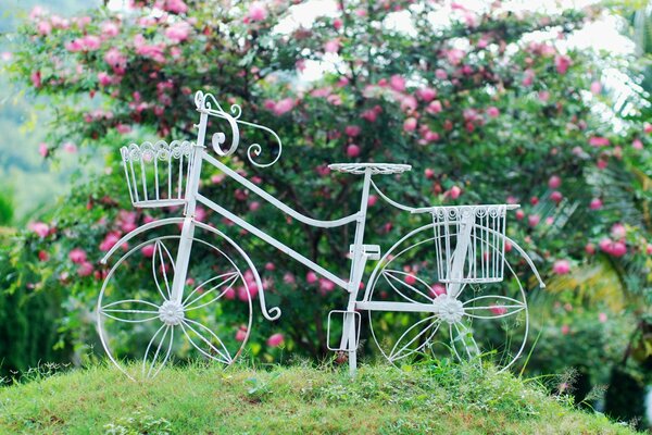 Instalacja białego roweru w krzakach kwitnących