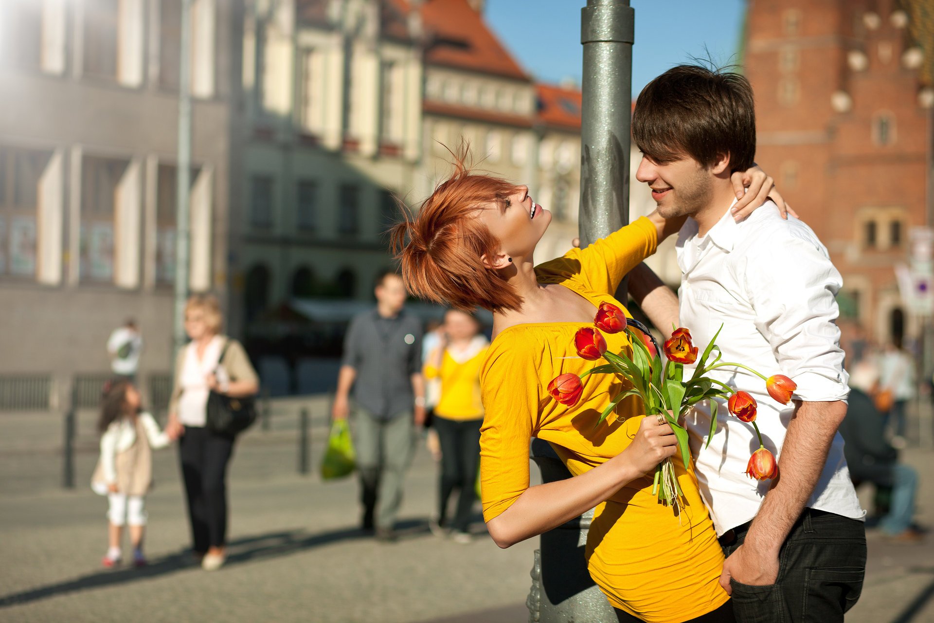 coppia ragazzo ragazza rossa vestito sorrisi pilastro città persone fiori bouquet tulipani positivo