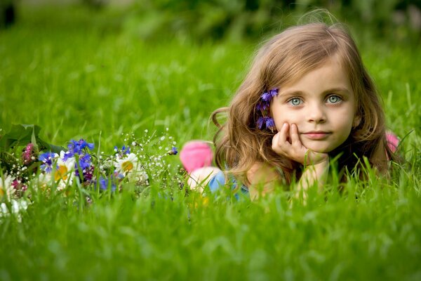 Ein Mädchen liegt in Blumen auf einem Feld