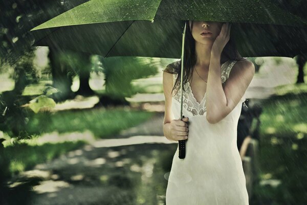 A girl under an umbrella in the summer rain