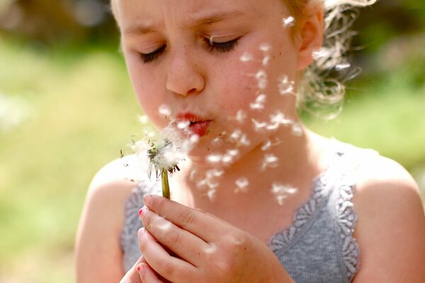 Serious girl blowing out a dandelion