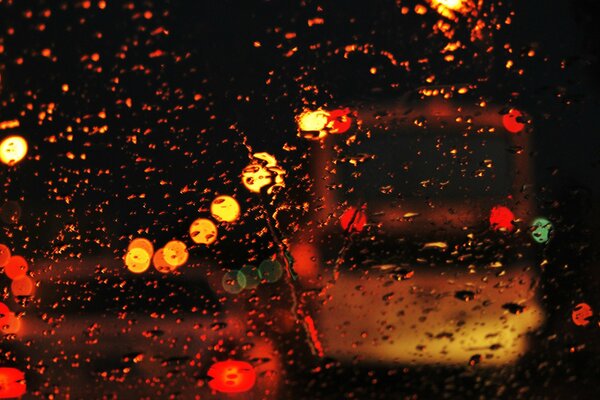 Lumières de la ville du soir à travers les gouttes sur le verre