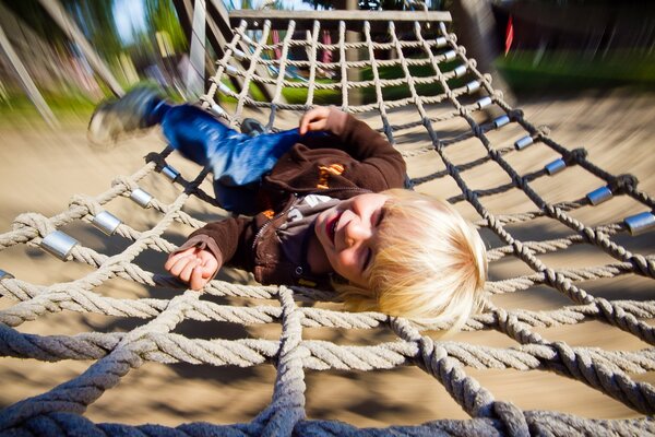 A boy in a good mood is lying in a hammock