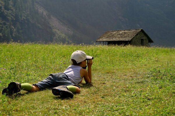 A boy watching a house in the grass