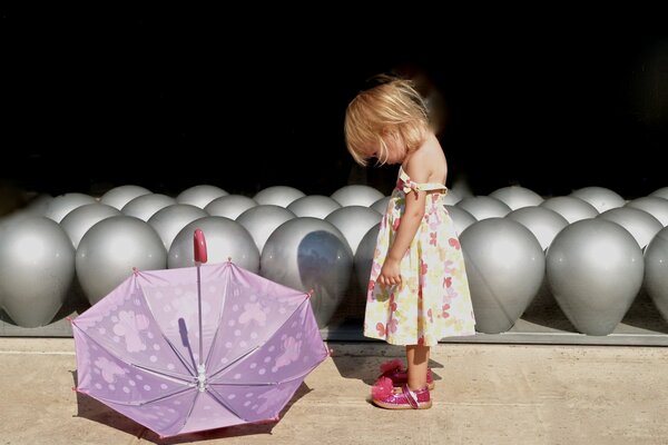 Ragazza con ombrello viola su sfondo di palloncini grigi