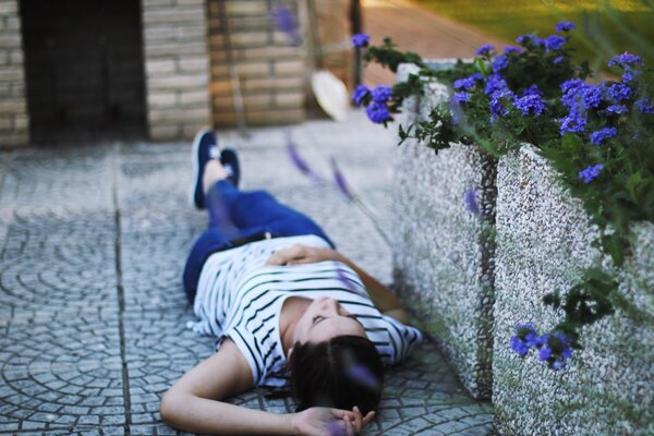 The girl lies on the asphalt and looks at the sky