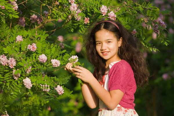 Mädchen hält einen Zweig eines Busches mit rosa Blüten