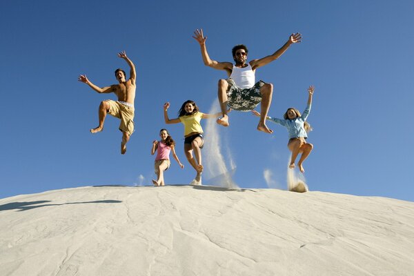 Joyeuse compagnie de jeunes gens sautant d une colline de sable