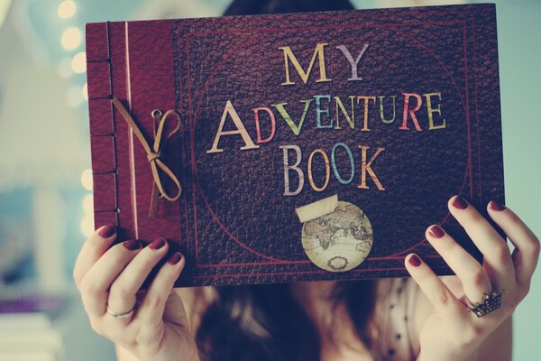 The girl is holding a book of adventures in her hands