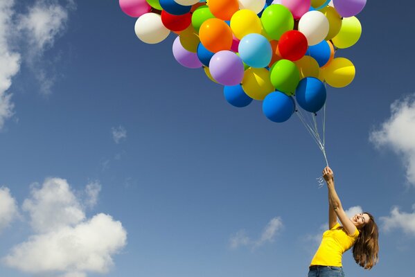 The girl holds a bunch of colorful balls