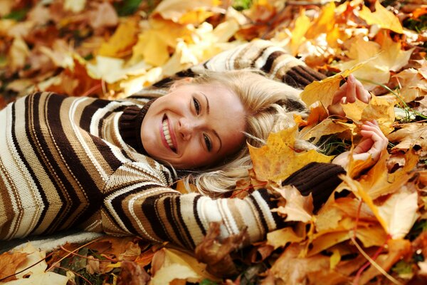 A happy girl lies on autumn leaves