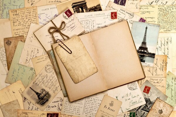 Zu einem alten Buch ist eine Büroklammer verbeugt, was ein altes Blatt ist und um die Briefe von Fotos und Briefmarken herum liegen