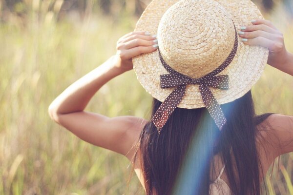 Chica de pelo oscuro posando en un sombrero en un campo en el verde