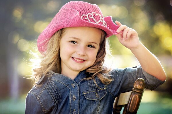 Nettes lächelndes Mädchen in einem Jeanshemd und einem rosa Cowboyhut