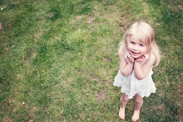 Chica con una sonrisa angelical en el fondo de la hierba
