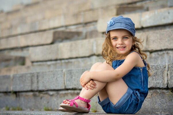 Девочка в кепке улыбается на улице