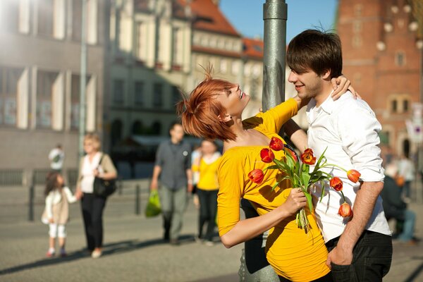 Rothaarige Mädchen im gelben Kleid mit Tulpen in der Hand