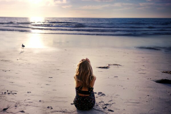 Jeune fille assise seule au bord de la mer