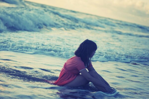 Chica sentada en el mar y disfrutando del agua de mar