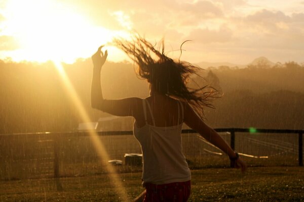 Ragazza che corre per incontrare il sole sotto la pioggia