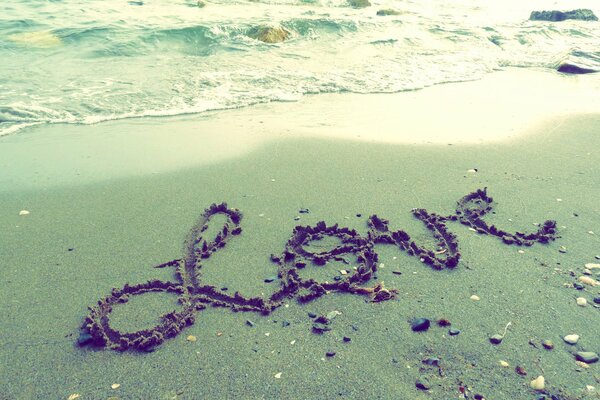 Die Inschrift Love auf dem nassen Sand, am Meer, am Strand