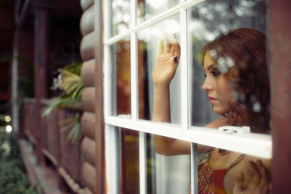 Bella ragazza pensosa guardando fuori dalla finestra