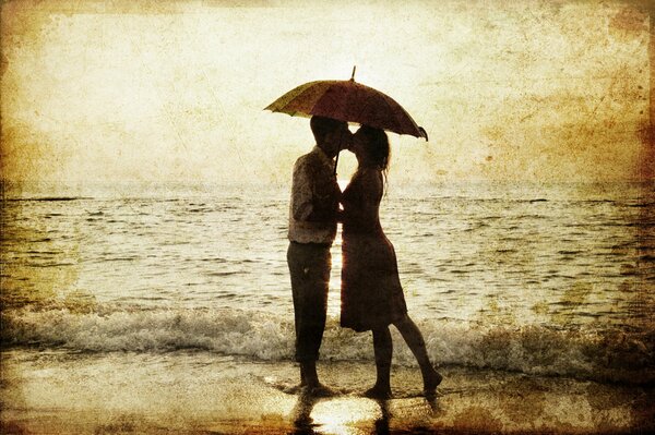Пара влюбленных на морском пляже целуются под зонтиком