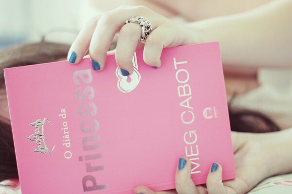 Девушка держит в руках розовую книгу