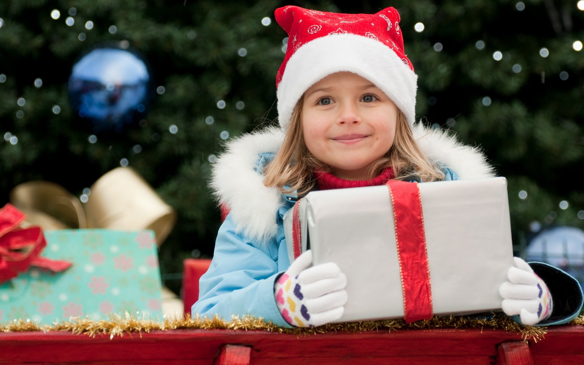 new year holiday vacation child girl smile happiness joy delight gift box gold ribbon bow blue jacket hat glove