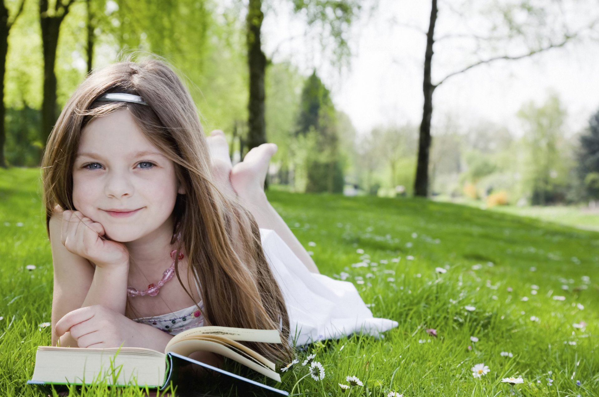 śliczna mała dziewczynka ładna blond szczęśliwa radość szczęście czytanie ogród park drzewa trawa śliczna dziewczyna śliczna piękna blondynka szczęśliwa książki dziecko dzieciństwo dzieci dziecko