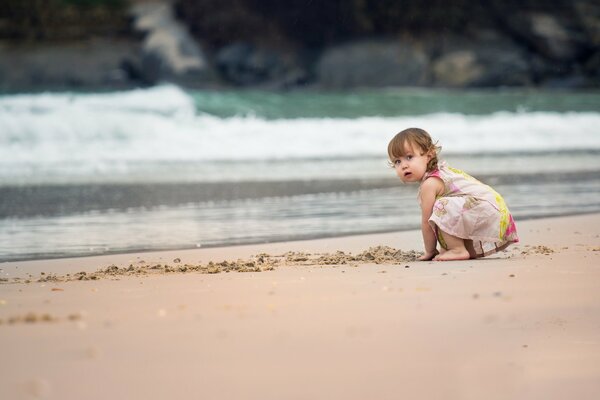 Fille sur la plage. Jouer avec le sable