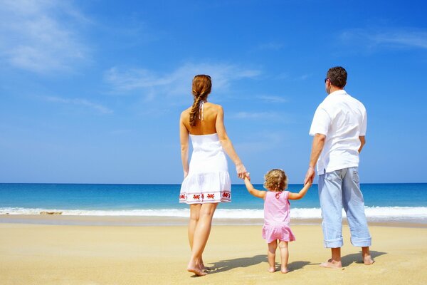 Family trio on a sandy beach, holding hands