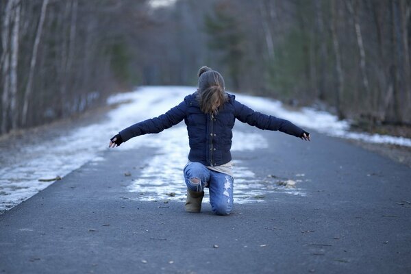 Fille assise sur une route enneigée