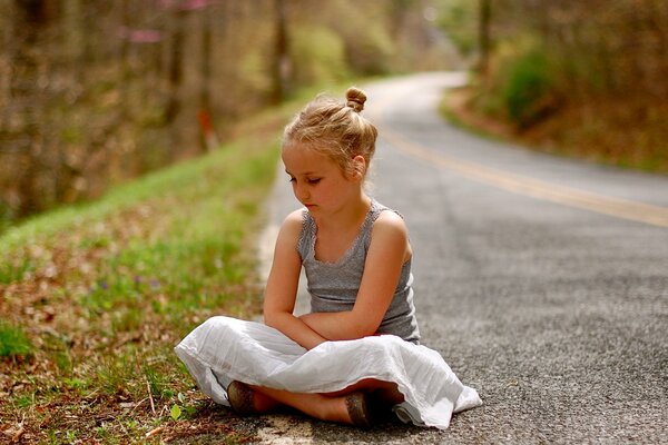 The girl is sitting on the road