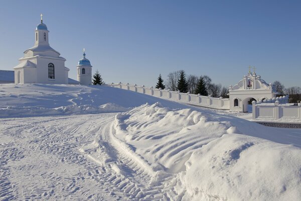 Das weiße Kloster vor dem Hintergrund des klaren blauen Himmels steht auf einem steilen, schneebedeckten Hügel