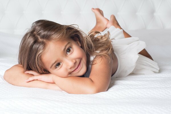 Bambino radiante sul letto di lusso